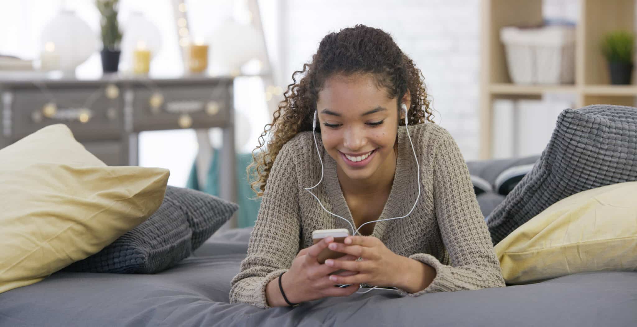 teen girl browses her phone with earbuds