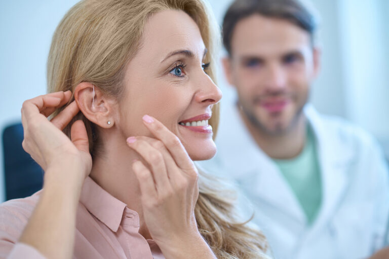 Woman touches hearing aid behind her ear