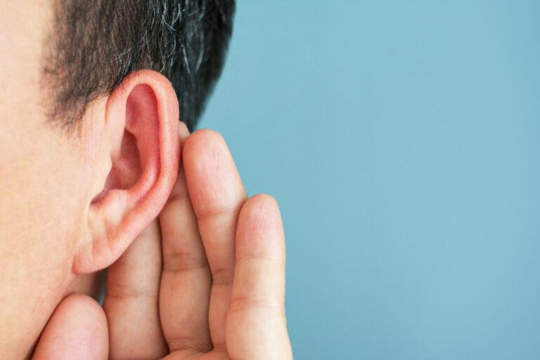 Close up of man holding hand behind ear to hear Close up of man holding hand behind ear to hear