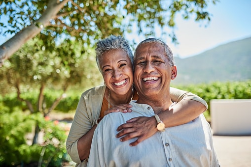 Happy couple embracing and smiling for the camera on a gorgeous summer day.